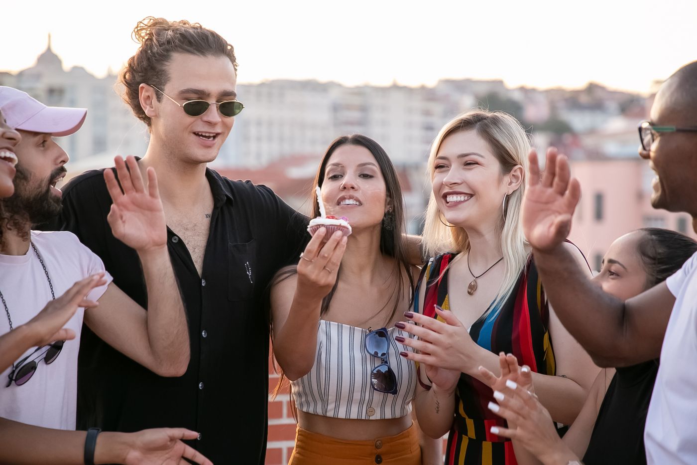 Friends celebrating a birthday on a rooftop terrace at sunset