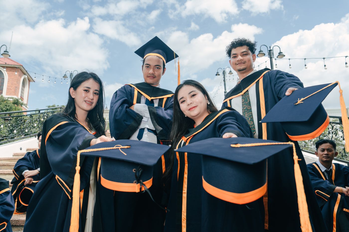Grupo de graduados con birrete y toga celebrando al aire libre